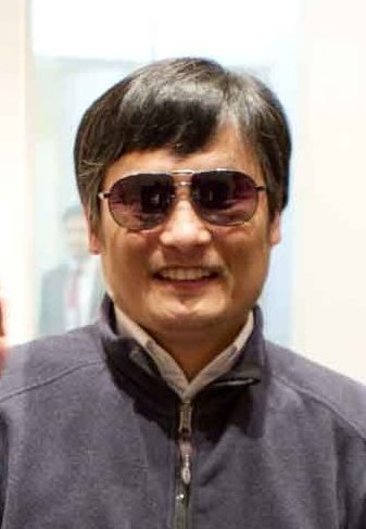 Chen Guangcheng wearing dark glasses and smiling toward the camera.