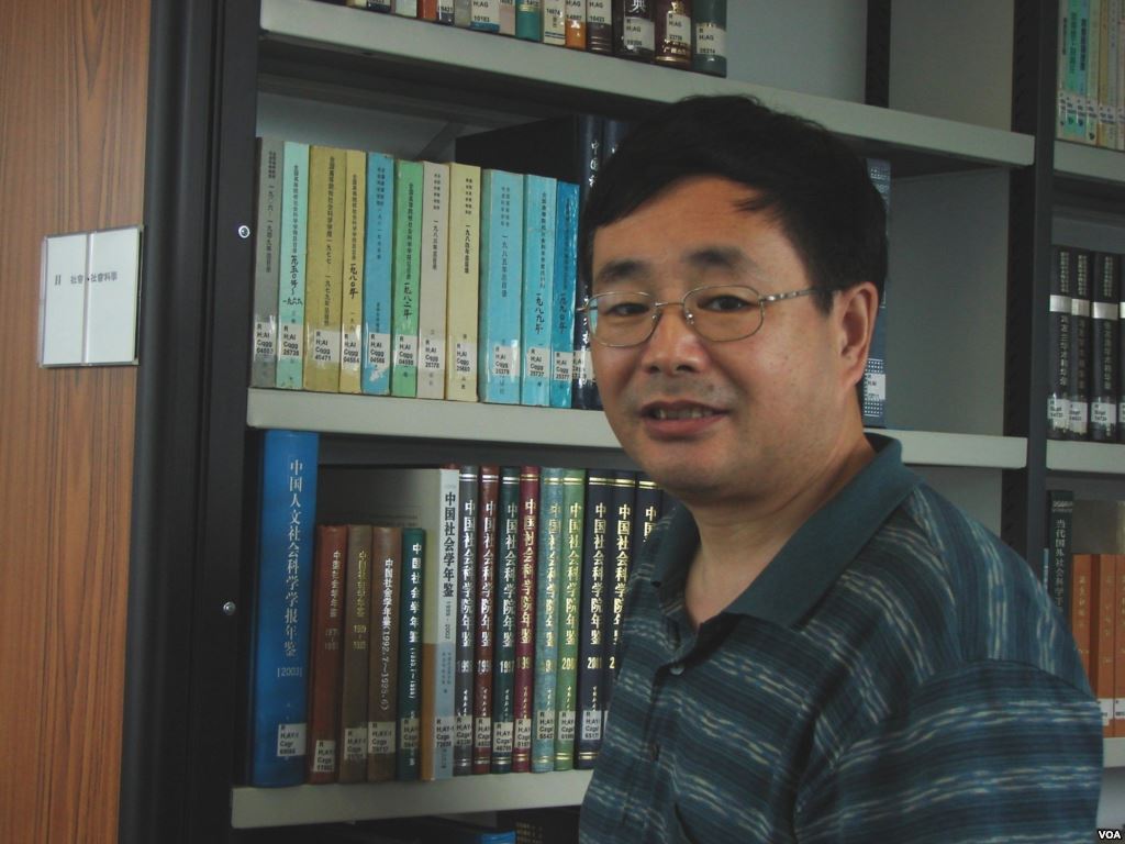 Chen Ziming wearing glasses beside bookshelves.