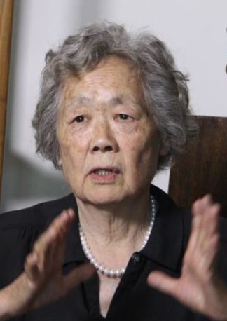 Ding Zilin seated and speaking, gesturing with both hands.