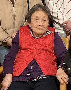 Gao Yaojie sitting in a chair wearing a red vest.