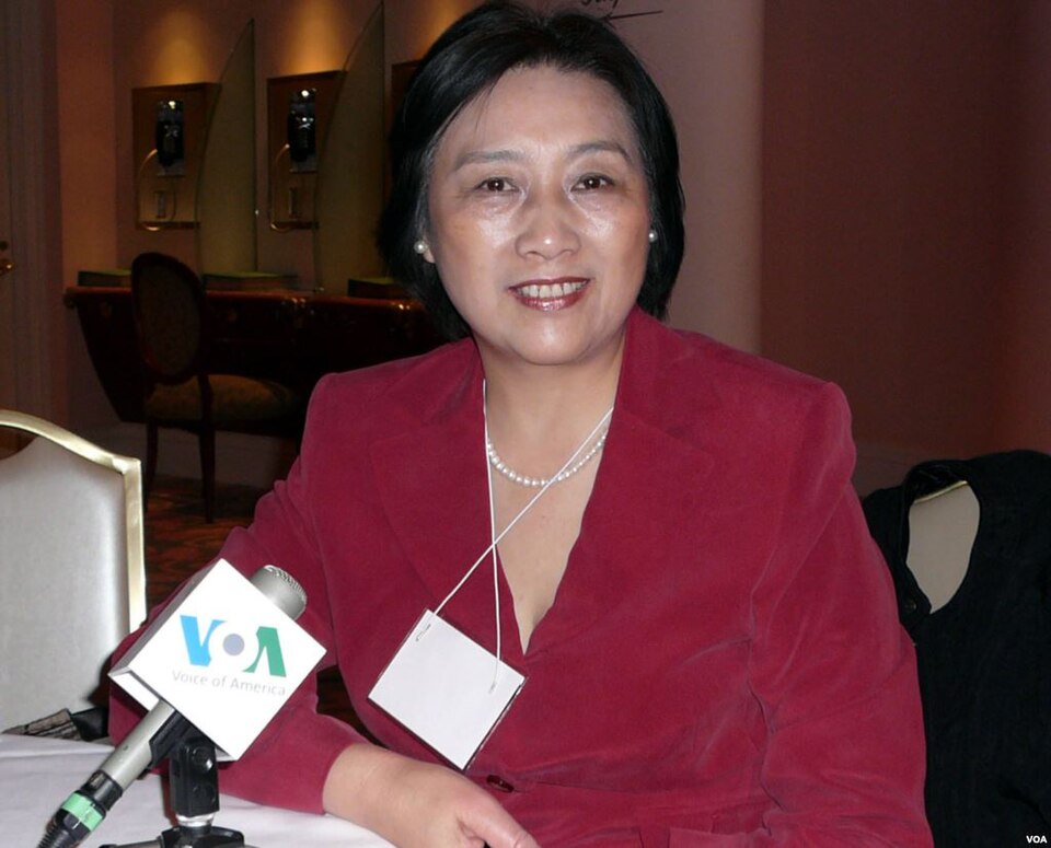 Gao Yu wearing a red jacket with microphones in front of her.