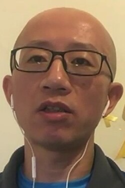 Hu Jia wearing glasses and earphones during a video interview.