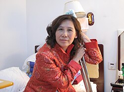 Ni Yulan seated in red clothing with crutches.
