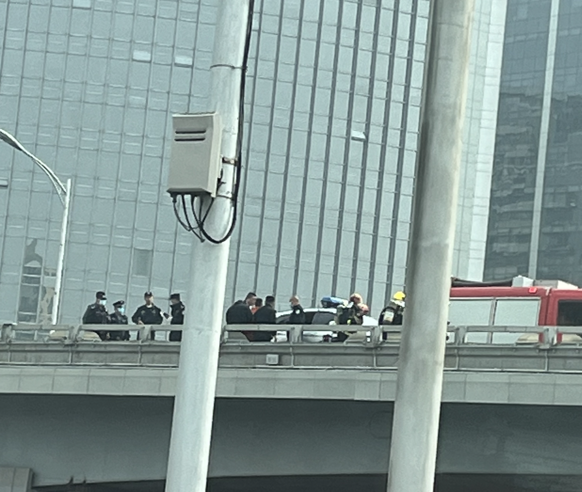 Uniformed personnel and a fire engine on a bridge, partly obscured by foreground columns.