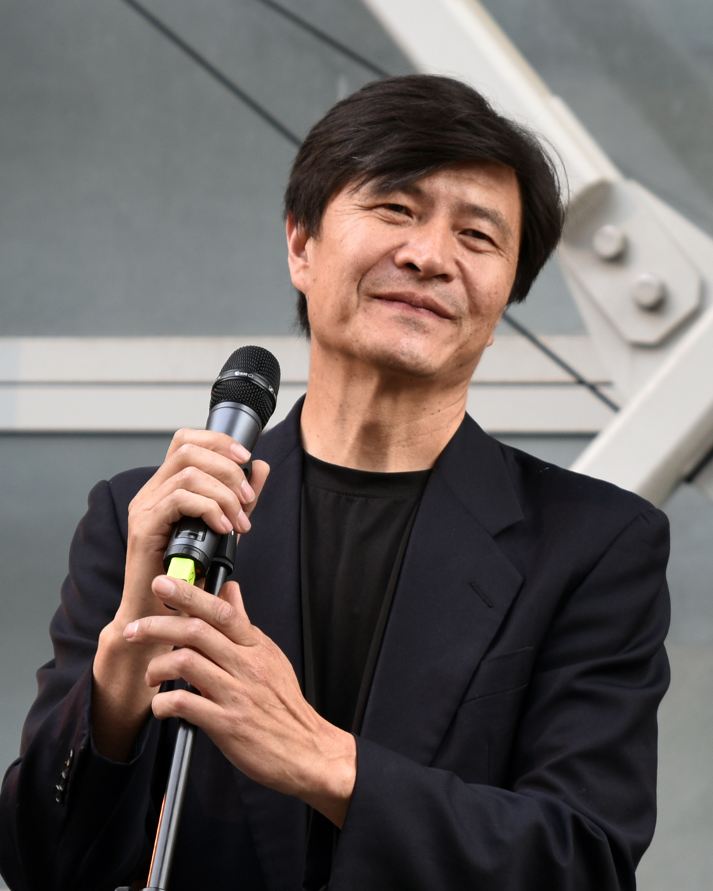 Zhou Fengsuo wearing a dark jacket and holding a microphone.